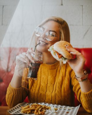 Eine Frau im Fast-Food-Restaurant mit Burger, Cola und Pommes